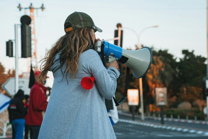 Promotorin mit Megafon im Straßeneinsatz einer Werbeaktion